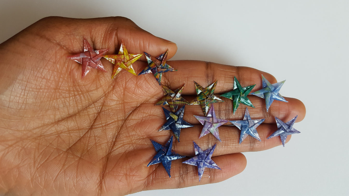 Hand holding colorful star-shaped studs against a white background.