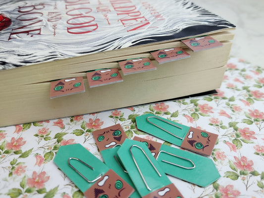 Book with decorative paper clips on a floral surface.